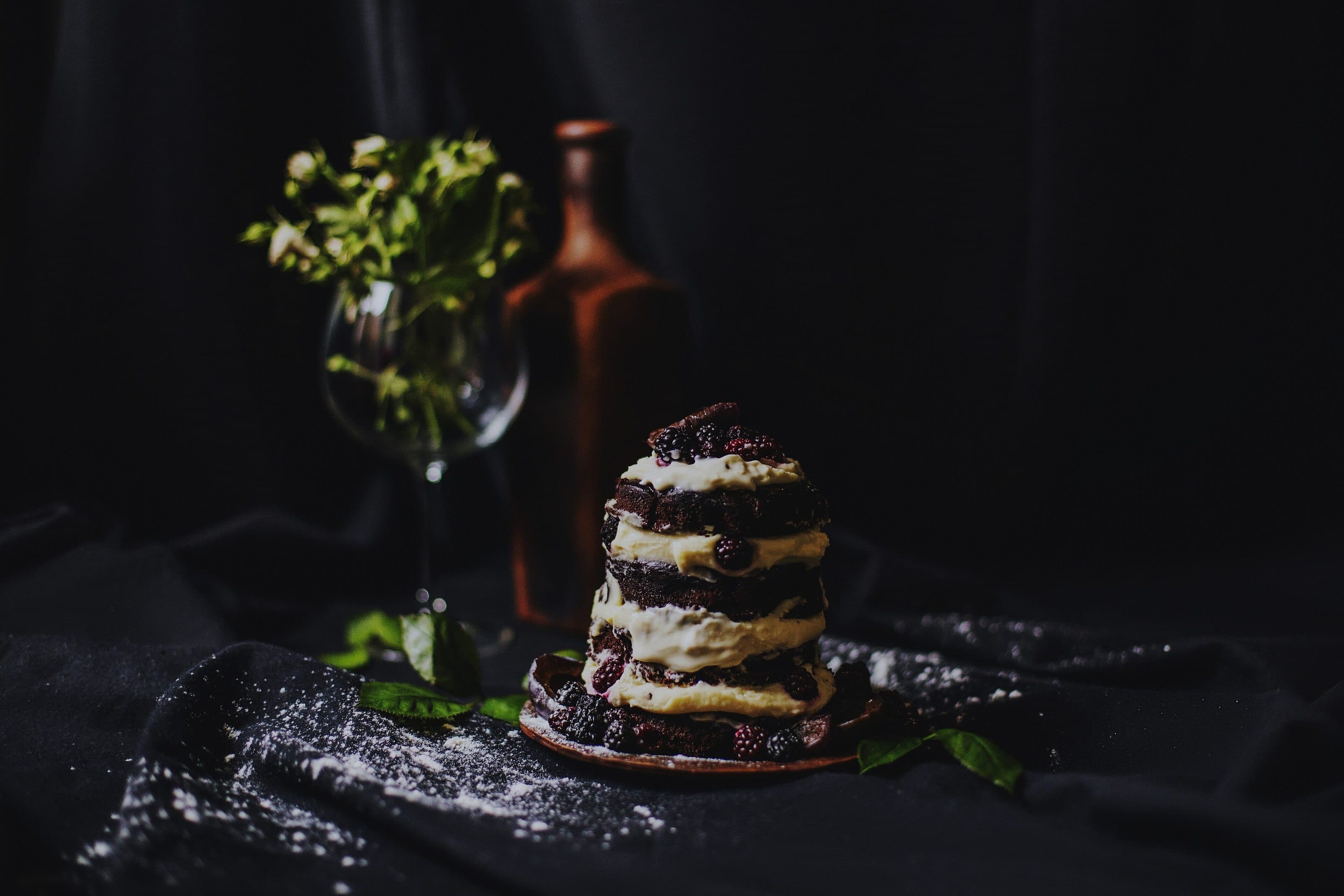 La torta a strati con la crema e le more, sul tavolo scuro